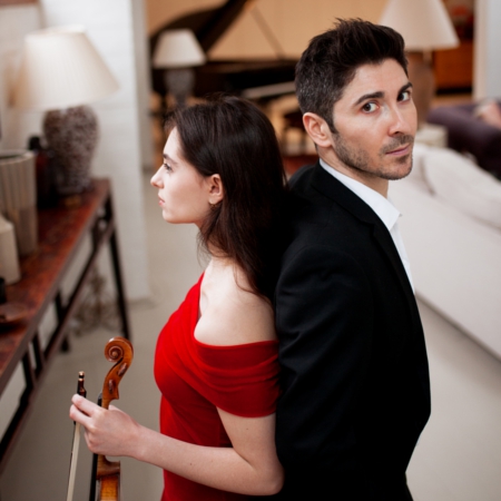 Esther Abrami and Niccolo Ronchi stand back to back. She holds her violin and the piano looms ominously in the background.