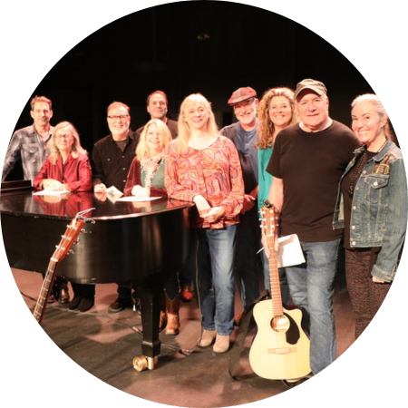 A group of past Singer Songwriters gather around.